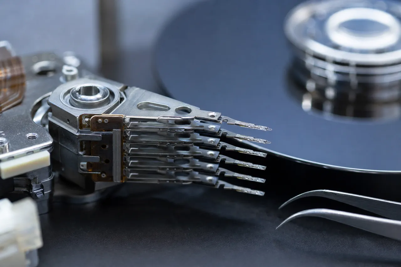 Macro view of a failed hard drive read/write head stack removed from a drive under bright magnification on a clean anti-static lab mat.