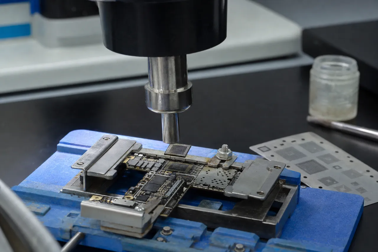 A precision hot-air rework station lifting a tiny processor chip off an iPhone logic board for a CPU and NAND transplant onto a donor board in the MDrepairs lab