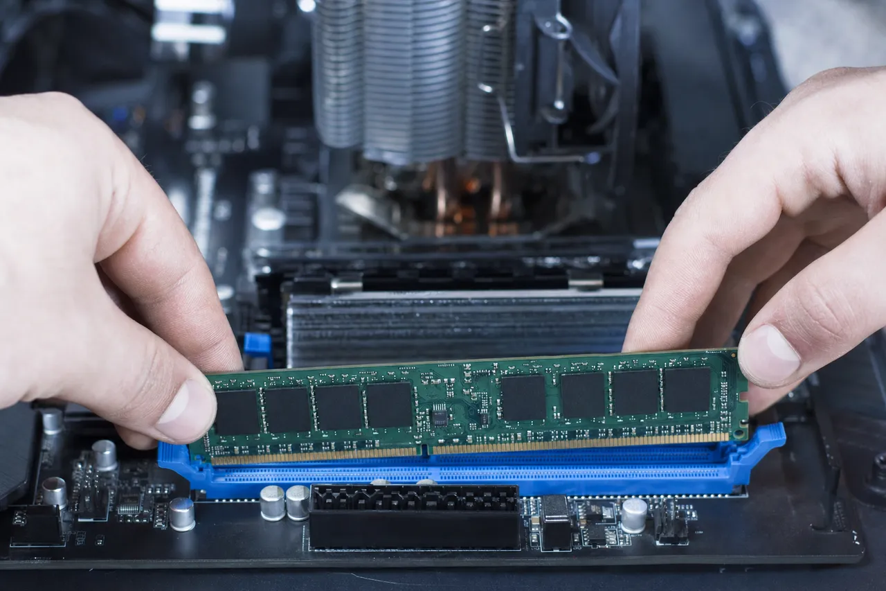A technician seating a DDR memory module into a desktop motherboard during a computer upgrade